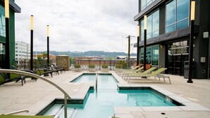 A rooftop pool area with multiple pools, lounge chairs, and a view of buildings and hills in the background. - Landing | Amazing Studio, Pool, Yoga Studio (Birmingham)