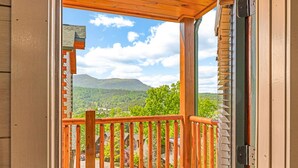 Un balcon en bois offrant une vue sur un paysage montagneux.