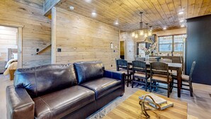 Un salon moderne avec un canapé en cuir, une table à manger en bois et un escalier menant à un autre niveau.