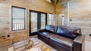 Un intérieur en bois avec un canapé en cuir, de grandes fenêtres et un plafond en bois.