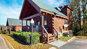 A log cabin with a porch, a satellite dish, and a chimney. - Adorable log cabin with front-back deck and hot tub (Pigeon Forge)