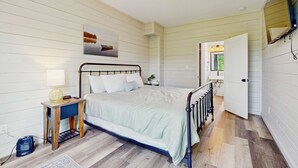 Ein Schlafzimmer mit Bett, Nachttisch, Lampe und einem Bild an der Wand.