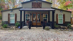 A rustic building with a porch, wooden shutters, and a metal roof. - Waterfront Cabin Retreat・Dock・Firepit・Grill・Games (Sharps Chapel)