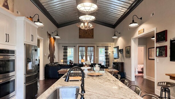 A spacious kitchen with a large island, stainless steel appliances, and a high ceiling with exposed beams. - Waterfront Cabin Retreat・Dock・Firepit・Grill・Games (Sharps Chapel)