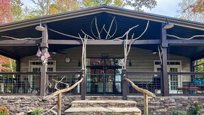 A lodge with a stone facade, a covered entrance, and a rustic design featuring wooden beams and antlers. - Waterfront Cabin Retreat・Dock・Firepit・Grill・Games (Sharps Chapel)