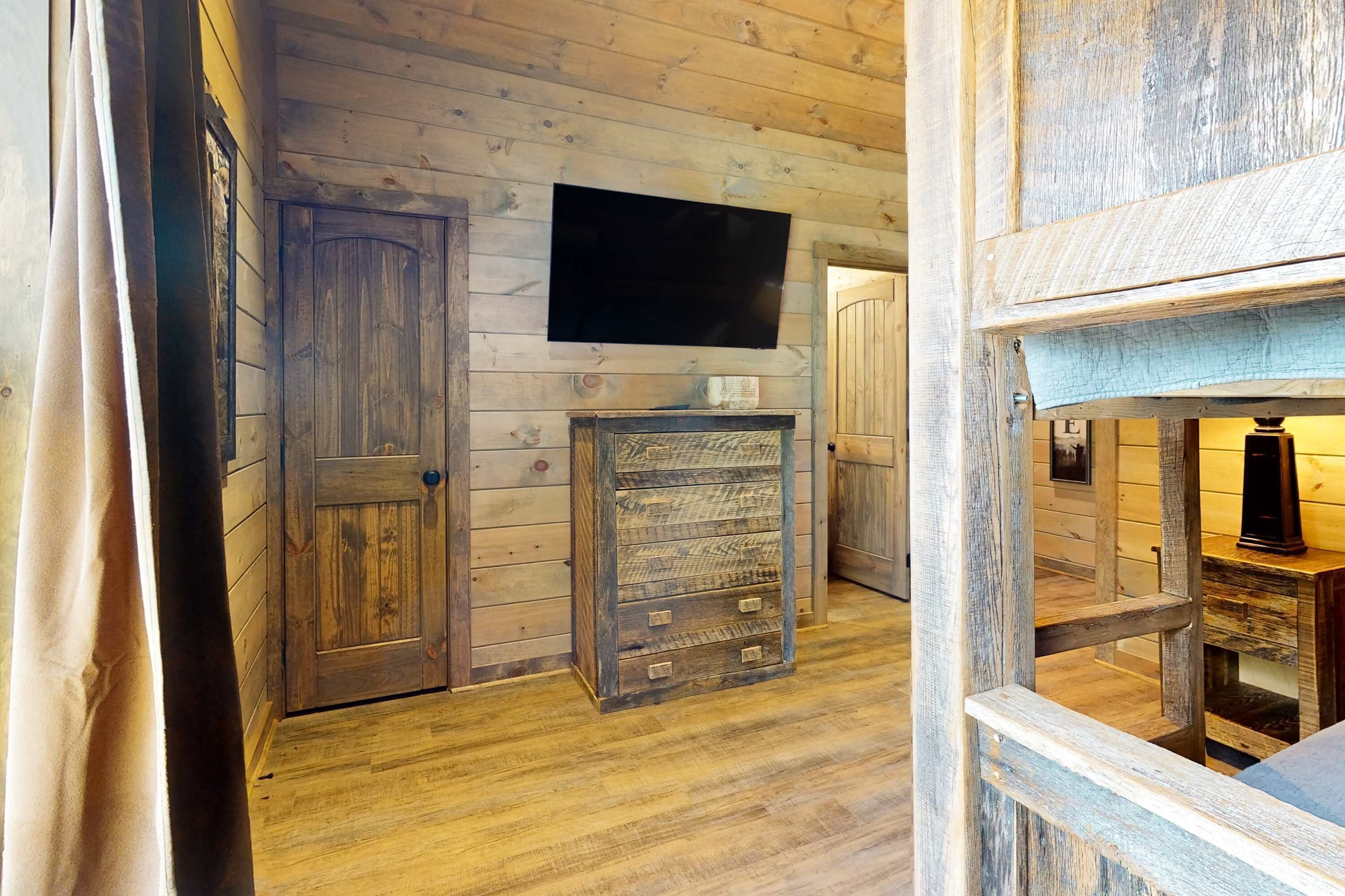 Un interior de madera con un televisor montado en la pared, un mueble de madera y una puerta.