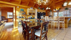A wooden cabin interior with a dining area, kitchen, and a large window. - Mtn View Cabin, Sleeps 12・Game Room・Hot Tub・Pool (Sevierville)