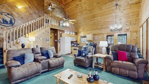 L’intérieur d’un chalet confortable en bois, avec un salon, une cuisine et un escalier menant à un étage supérieur.
