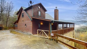 Une cabane rustique en rondins de bois, dotée d’un balcon et d’une cheminée.