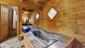 L’intérieur d’un chalet en bois comprend deux bains à remous, une salle de bain avec douche et un plafond en bois.