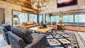 L’intérieur d’un chalet confortable, avec un grand lustre, des canapés en cuir et un tapis à motifs.