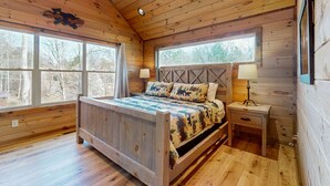 Ein Schlafzimmer einer Holzhütte mit einem Bett, zwei Nachttischen und einem Deckenventilator.