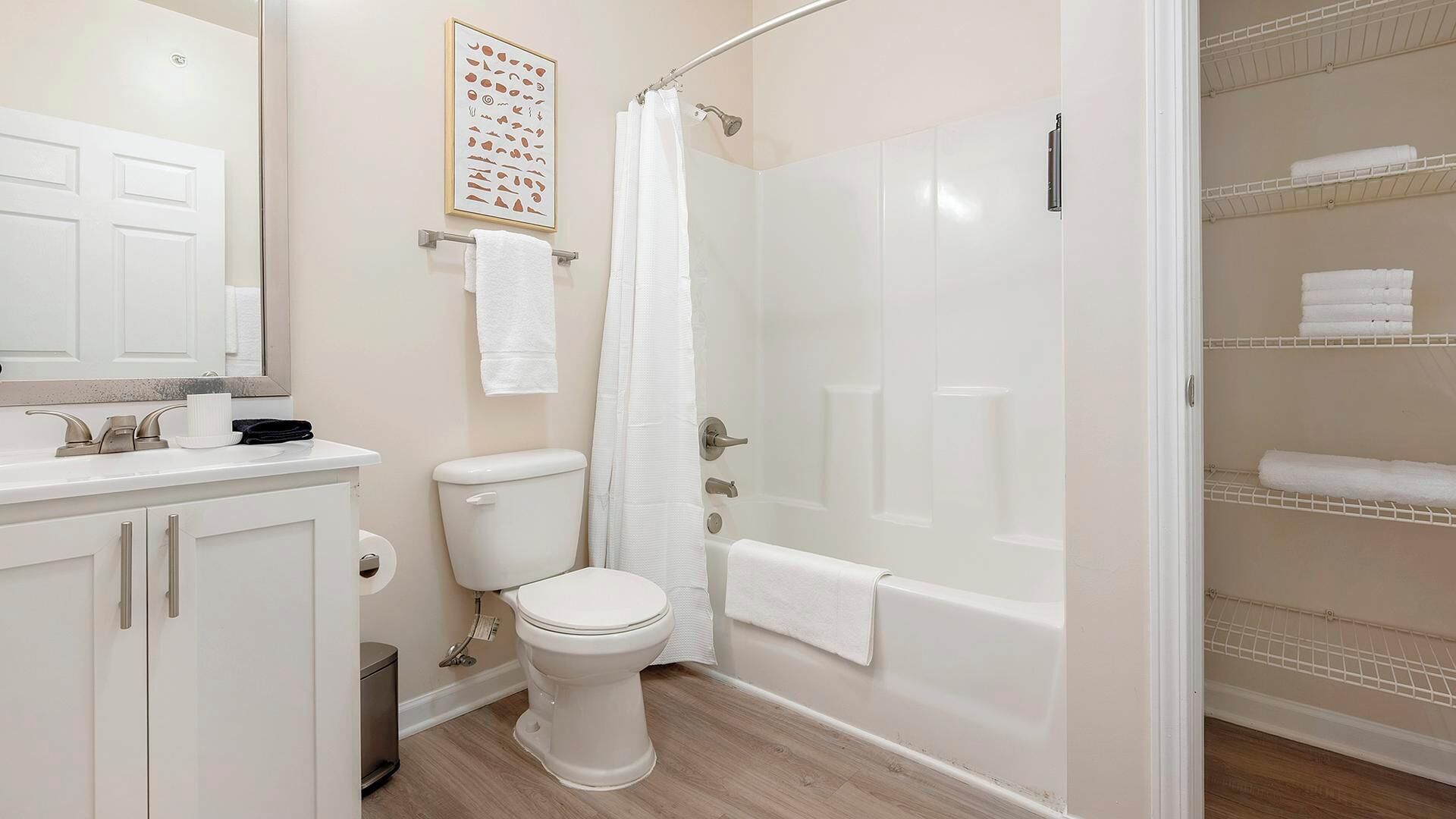 Ein Badezimmer mit Toilette, Waschbecken und Dusche. Handtuchhalter und Duschvorhang sind vorhanden.
