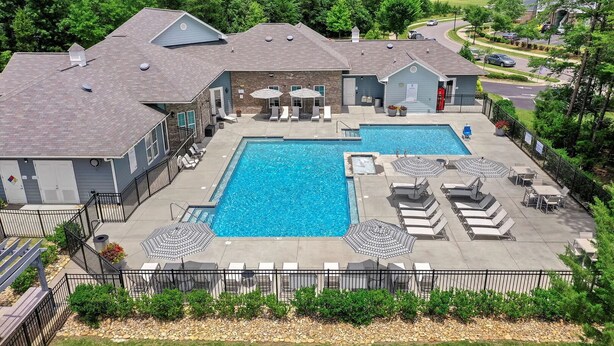 A residential property with a large rectangular swimming pool, outdoor seating area with umbrellas, and a fenced yard. - Landing | Chic 2BD, Gym, Clubhouse (Concord)