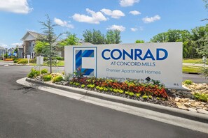 A sign for CONRAD at Concord Mills, indicating it is a premier apartment home. - Landing | Beautiful 2BD, Clubhouse, Gym (Concord)