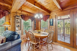 A wooden cabin interior with a dining table, chairs, a sofa, and a chandelier. - Panoramic Mountain Views, Secluded Cabin, Hot Tub (Sevierville)