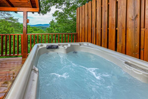 A hot tub on a wooden deck with a view of lush greenery and mountains. - Panoramic Mountain Views, Secluded Cabin, Hot Tub (Sevierville)