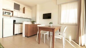Una cocina moderna con armarios blancos, una mesa de comedor de madera y un televisor montado en la pared.