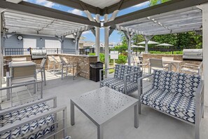 An outdoor patio with a grill, seating area, and a covered section. - Landing | Stunning 1BD, Clubhouse, Gym (Concord)
