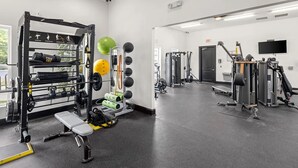 Ett gym med en knäböjsställning, en bänk och diverse träningsredskap.