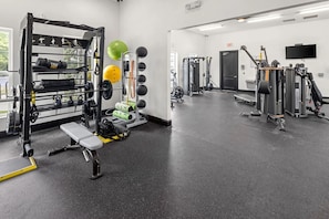 A gym with a squat rack, bench, and various exercise equipment. - Landing | Stunning 1BD, Clubhouse, Gym (Concord)