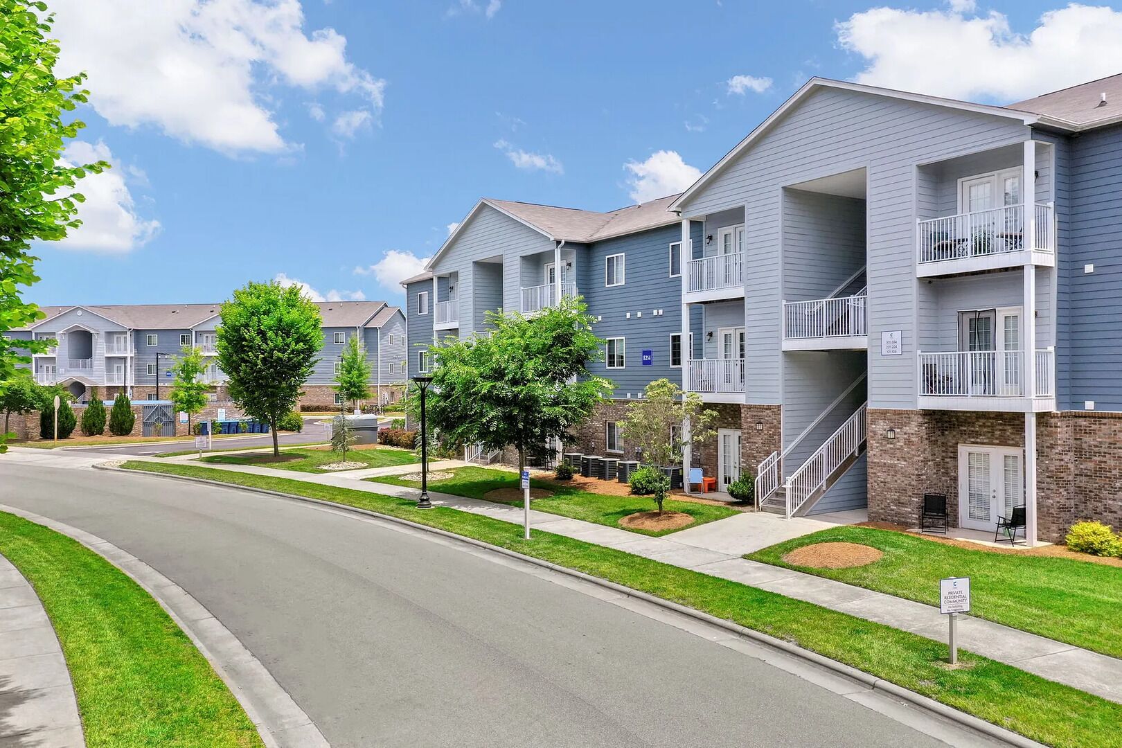 A residential building with multiple floors, balconies, and a well-maintained lawn.