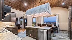 A spacious kitchen with granite countertops, a central island, and a large overhead ventilation system. - Mtn View Home, Sleeps 8・Fireplace・Games・Hot Tub (Sevierville)