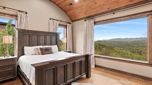 A bedroom with a large bed, wooden ceiling, and a view of a forested landscape. - Mtn View Home, Sleeps 8・Fireplace・Games・Hot Tub (Sevierville)