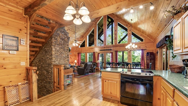 A spacious wooden cabin with a large kitchen, stone fireplace, and a stone staircase. - Forested Hideaway, Sleeps 14・Hot Tub・Pool Access (Sevierville)
