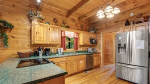 A wooden cabin-style kitchen with granite countertops, stainless steel appliances, and wooden cabinets. - Forested Hideaway, Sleeps 14・Hot Tub・Pool Access (Sevierville)