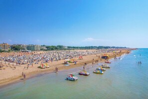Uma praia com vários guarda-sóis e pessoas.