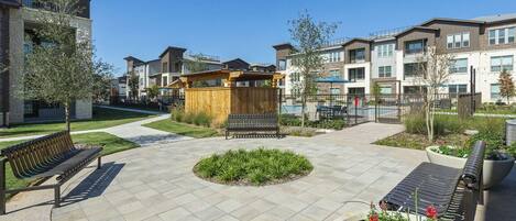 A courtyard with benches, a wooden structure, and a pool area surrounded by modern buildings.