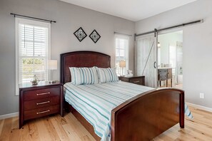 A bedroom with a wooden bed, a nightstand, a dresser, and a large window with blinds. - Huge View Deck, Game Room Fun, Fire pit Evenings (Sevierville)