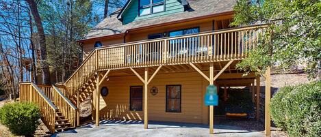 A two-story lodge with a wooden deck and a covered porch.