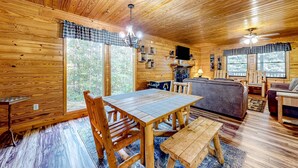 A wooden cabin interior with a dining table, chairs, a sofa, and a television. - Homey Cabin W Hot Tub・2 Porches・Pool Table・Games (Pigeon Forge)
