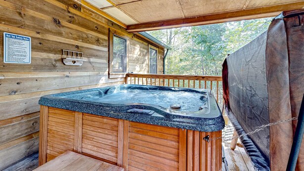 A wooden cabin with a hot tub, wooden walls, and a view of trees. - Homey Cabin W Hot Tub・2 Porches・Pool Table・Games (Pigeon Forge)