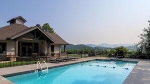 Una piscina con vistas a montañas, un porche cubierto y un jardín vallado.