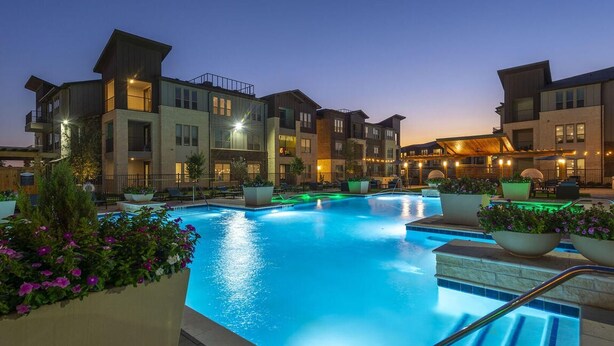 A swimming pool surrounded by multi-story buildings with balconies, outdoor seating, and potted plants. - Landing | Stylish 2BD, Gym, Pool (Katy)