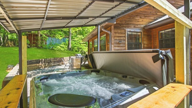 A hot tub with a wooden deck, a covered patio, and a wooden house in the background. - Tranquil Cabin W Hot Tub・Boat / Motorcycle Parking (Sevierville)