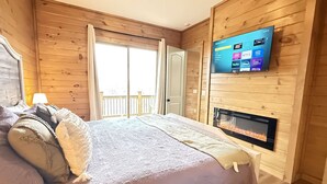 Um quarto aconchegante com uma cama, uma televisão na parede e uma lareira.