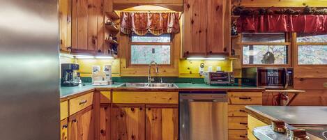 A wooden cabin-style kitchen with a sink, dishwasher, and stove.