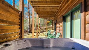 Una cabaña de madera con jacuzzi, terraza de madera y un área de patio techada.