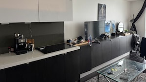 A modern kitchen with a built-in stove, a coffee maker, and various kitchen items on the counter. - Iceboat Elegance Suites (Toronto)