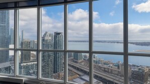 A high-rise building with large windows offering a view of a cityscape and a body of water. - Iceboat Elegance Suites (Toronto)