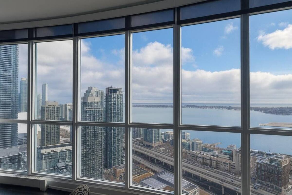 Un edificio alto con amplios ventanales que ofrece vistas a un paisaje urbano y una masa de agua.
