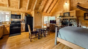 A log cabin interior with a kitchen, dining area, and a fireplace. - Charming Dog Friendly Cabin・Hot Tub・Scenic View (Sevierville)