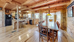A wooden cabin interior with a dining area, kitchen, and bar. - Charming Dog Friendly Cabin・Hot Tub・Scenic View (Sevierville)