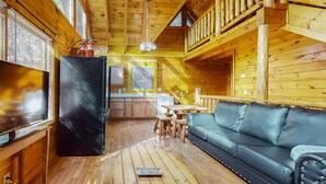 A wooden cabin interior with a black refrigerator, wooden dining table, and a leather sofa. - 5 Mi to Pigeon Forge・Cozy Escape・Dog Welcome・Views (Sevierville)