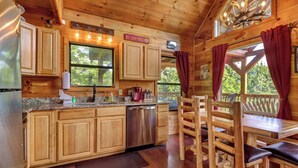 A wooden cabin interior with a kitchen area, dining table, and chairs. - 8.6 Mi to Dollywood・Serene Cabin Getaway・Hot Tub (Sevierville)
