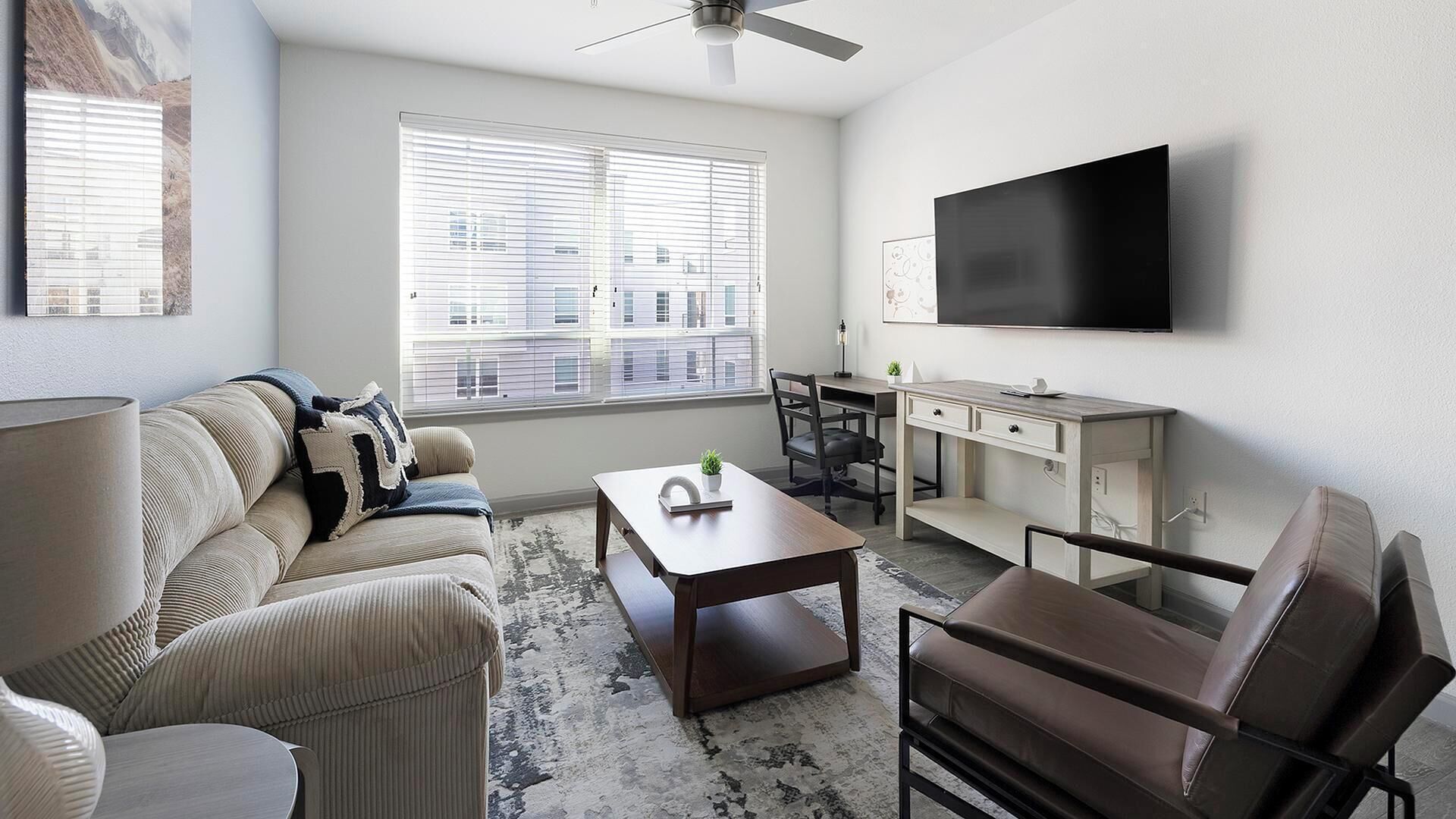 A modern living room with a sofa, coffee table, and a TV mounted on the wall.